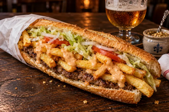 Une mitraillette&nbsp;: une demi-baguette garnie de steak haché, de frites, de crudités et de sauce, dans son papier de friterie.
